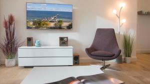 ein Wohnzimmer mit einem Stuhl und einer weißen Kommode in der Unterkunft SPA Apartment FIRST Sellin in Ostseebad Sellin + 17 Fotos