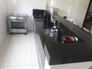 una cucina con piano di lavoro, lavandino e piano cottura di Paraíso Escarpas do Lago 1 - Capitólio a Capitólio