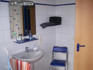 a bathroom with a sink and a mirror and a chair at Ferienwohnung Mauer, Wohnung "C" in Heede
