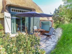 eine Terrasse mit Tisch und Stühlen und einem Sonnenschirm in der Unterkunft S4 im Friesenhaus Sara in Wenningstedt-Braderup