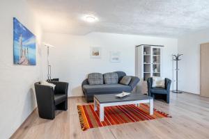 a living room with a couch and two chairs at Ferienwohnung Flut mit Loggia und schönem Ausblick am Badesee Tannenhausen in Aurich