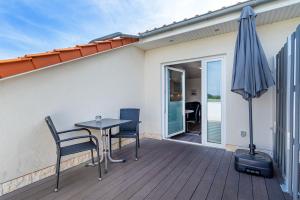 a patio with a table and chairs and an umbrella at Ferienwohnung Flut mit Loggia und schönem Ausblick am Badesee Tannenhausen in Aurich +12 photos