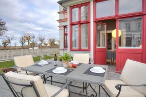 a patio with a table and chairs and a red door at Villa Seeblick Schloonsee in Ahlbeck
