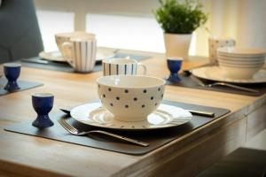 a table with a coffee cup and plates and utensils at FeWo Dünenquartier Cuxhaven - ideal für Familien und Paare in Cuxhaven