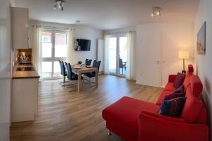 a living room with a red couch and a table at FeWo Dünenquartier Cuxhaven - ideal für Familien und Paare in Cuxhaven