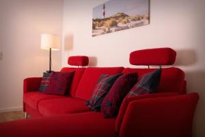 a red couch with pillows in a living room at FeWo Dünenquartier Cuxhaven - ideal für Familien und Paare in Cuxhaven