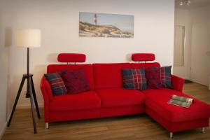 a red couch in a living room with a lighthouse at FeWo Dünenquartier Cuxhaven - ideal für Familien und Paare in Cuxhaven