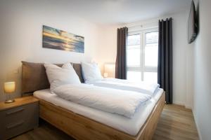 a bedroom with a bed with white sheets and a window at FeWo Dünenquartier Cuxhaven - ideal für Familien und Paare in Cuxhaven +17 photos