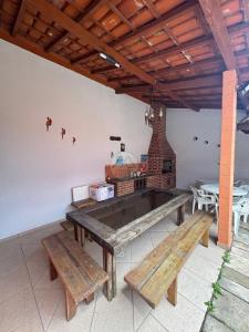 a patio with benches and a table and a fireplace at CASA DUPLEX Jardim São Lourenço in Bertioga