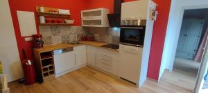 a small kitchen with white cabinets and a red wall at Birkennest in Bingerbrück +15 photos