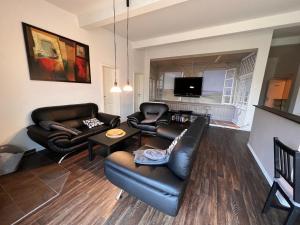 a living room with leather furniture and a tv at Leuchtfeuer Fewo "Catrin" in Börgerende-Rethwisch