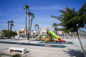 un parco giochi con scivolo in un parco con palme di Casa Elshani en Lo Pagan para hasta 6Pax HHH a San Pedro del Pinatar
