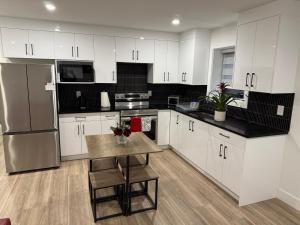 a kitchen with white cabinets and a table with chairs at Calm & Cozy Private Suite in Surrey
