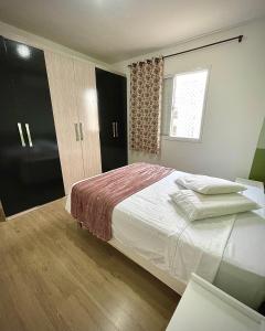 a bedroom with a large bed and a window at Ap de 2 quartos com AR, wifi e garagem - Bairro tranquilo in Santo Ângelo +6 photos