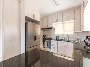 a kitchen with white cabinets and a black counter top at Capri House in Cape Town