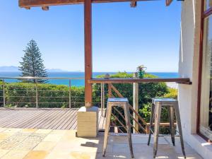 a table and two stools on a balcony with the ocean at St James Pool Cottage in St. James