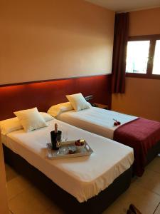 2 camas en una habitación de hotel con bandeja de comida en Hotel Jonquera, en La Jonquera