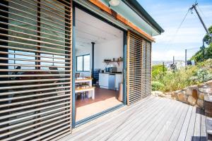 a pivot door opens up to a kitchen with a deck at Modern Beach Apartment in Kalk Bay