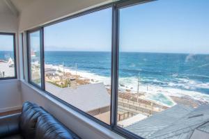 a room with a view of the beach and the ocean at Modern Beach Apartment in Kalk Bay