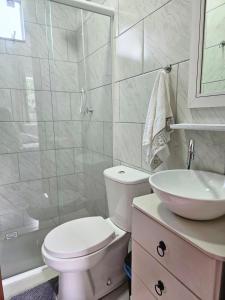 ein weißes Badezimmer mit Toilette und Waschbecken in der Unterkunft Studio com ar condicionado e estacionamento gratuito próximo ao aeroporto e praias in Florianópolis