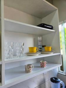 ein Regal mit Bechern und Tellern darauf in der Unterkunft Studio com ar condicionado e estacionamento gratuito próximo ao aeroporto e praias in Florianópolis