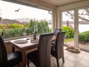 a dining room with a table and chairs and a large window at Ferienhaus SEERESIDENZ am Mühlensee in Godern