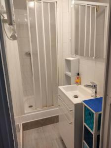 a white bathroom with a shower and a sink at Villa Les Palmiers in Saint-Jean-de-Monts