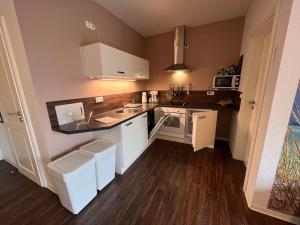a small kitchen with white appliances and wooden floors at Leuchtfeuer Fewo "Kimberly" in Börgerende-Rethwisch