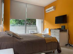 Un dormitorio con una cama y un televisor y una ventana. en SOLAR DEL ABASTO, en Buenos Aires