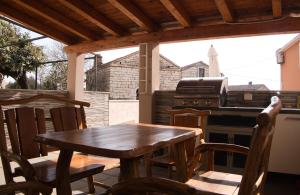 a wooden table and chairs on a patio with a grill at Ferienhaus Maja in Pavicini