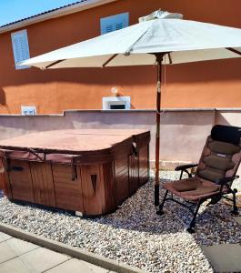a hot tub with an umbrella next to a chair at Ferienhaus Maja in Pavicini