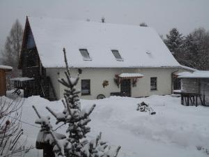a snow covered house with a snow covered roof at Zum Hecht, FeWo Spitzberg in Herrnhut