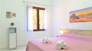 a bedroom with a pink bed with two towels on it at Ferienhaus Casa Lavanda - Villaggio Galanu in Li Valcaggi