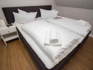ein Bett mit weißer Bettwäsche und einem Handtuch darauf in der Unterkunft FerienDüne 7 in Kägsdorf