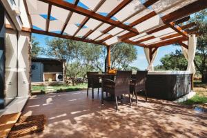 a patio with a table and chairs under a wooden pergola at House Stone house with jacuzzi in Lukoran