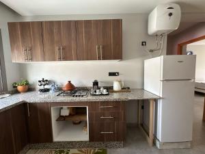 a kitchen with wooden cabinets and a white refrigerator at Sand house in Oualidia