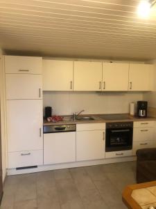 a kitchen with white cabinets and a stove at Ferienhaus Ostfriesland in Berumbur