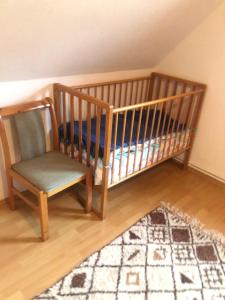 a crib and a chair in a room with a rug at Ferienhaus Ostfriesland in Berumbur +11 photos