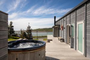 a hot tub on a deck next to a building at Ocean Beach Retreat, Stylish, Prime Beachfront in Raglan