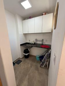 a small kitchen with a sink and white cabinets at Apartamento confortável José menino in Santos