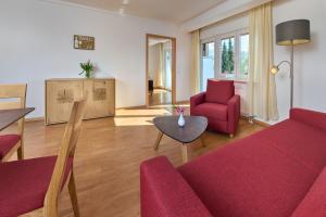 a living room with a red couch and a table at Thermen Appartements Gabriela, Appartement 50 qm in Bad Krozingen