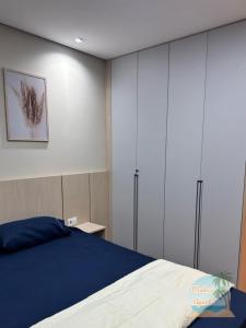 a bedroom with a blue bed and white cabinets at Mabasi Apart- Palladium - São Vicente in São Vicente +7 photos