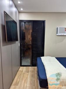 a bedroom with a bed and a flat screen tv at Mabasi Apart- Palladium - São Vicente in São Vicente