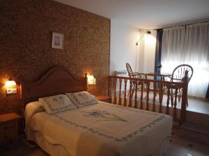 1 dormitorio con 1 cama, mesa y sillas en Hostal Yuste, en Garganta la Olla