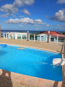 a blue swimming pool with the ocean in the background at La source bis, Mer et source d'eau chaude in Bouillante
