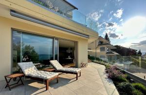 a patio with two chairs and a large window at LAKEVIEW - 2 bedroom stay with Sauna and parking on Lake Constance in Berlingen