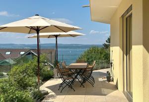 a table and chairs with an umbrella on a patio at LAKEVIEW - 2 bedroom stay with Sauna and parking on Lake Constance in Berlingen