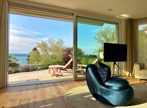 a living room with a black chair and a sliding glass door at LAKEVIEW - 2 bedroom stay with Sauna and parking on Lake Constance in Berlingen +28 photos