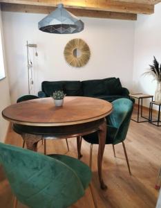 a living room with a wooden table and green chairs at Rösslerhof Ferienwohnung Rösslerweiher in Schlier-Unterankenreute +17 photos