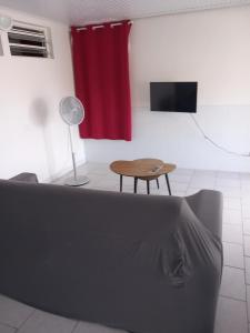 a room with a couch and a table and a red curtain at La source bis, Mer et source d'eau chaude in Bouillante